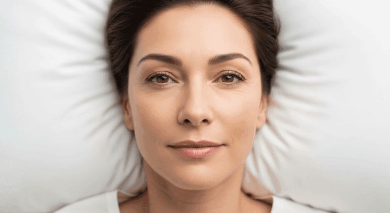 A close-up portrait of a woman with a serious expression, looking directly at the camera. The background is blurred with white, radial patterns.